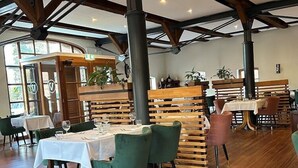 Un ristorante con travi in legno, sedie rivestite in verde e tovaglie bianche.