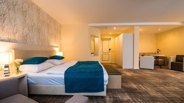 Una camera d'albergo con un letto, comodini, una scrivania, una sedia e un tavolino con un vaso di fiori.