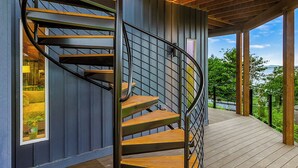 Una escalera de caracol con escalones de madera y barandillas de metal en un edificio moderno con suelo de madera y ventanas amplias.
