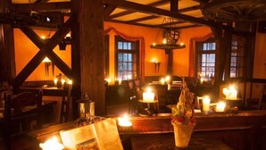 A cozy restaurant interior with wooden beams, candle-lit tables, and a rustic ambiance. - Eisenacher Hof (Eisenach)