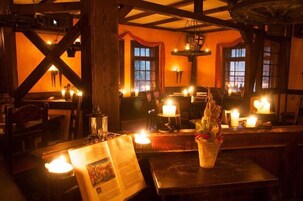 Un acogedor interior de restaurante con vigas de madera, mesas iluminadas con velas y un ambiente rústico.