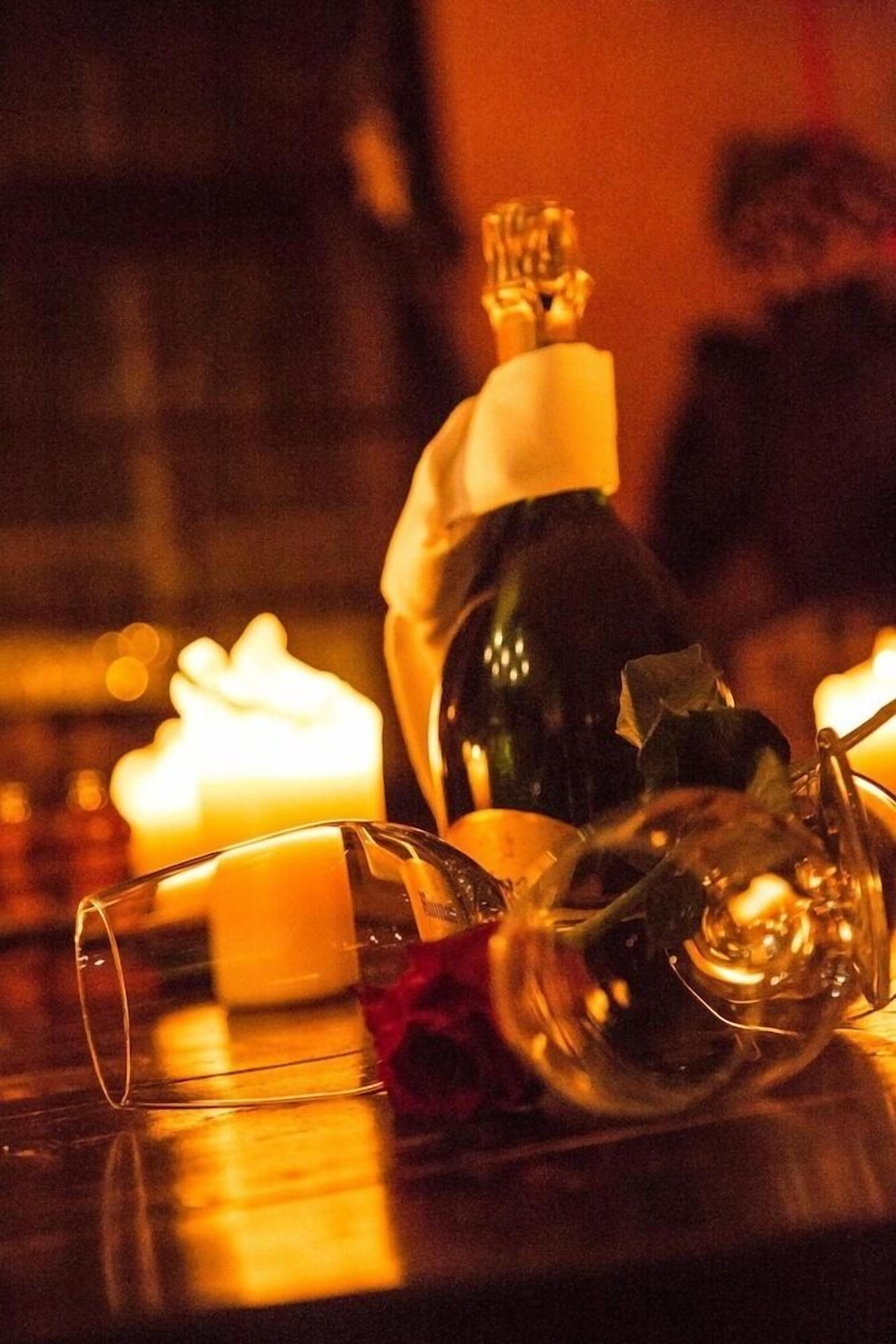 Une table avec une bouteille, un verre et une bougie.