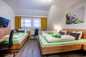 Une chambre d’hôtel avec deux lits, un bureau, une chaise, une télévision et un tableau au mur.