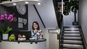 A reception area with a clock, a desk with a bowl and flowers, and a staircase. - Seerose (Lindau)