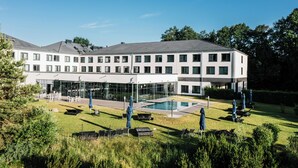 A modern building with a swimming pool, outdoor seating, and a well-maintained lawn. - A-ja Bad Saarow. Das Resort (Bad Saarow)