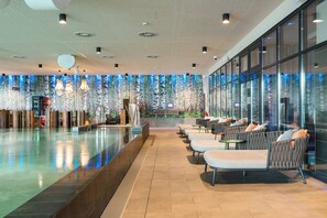 A modern hotel lobby with a pool, seating area, and large windows. - A-ja Bad Saarow. Das Resort (Bad Saarow)