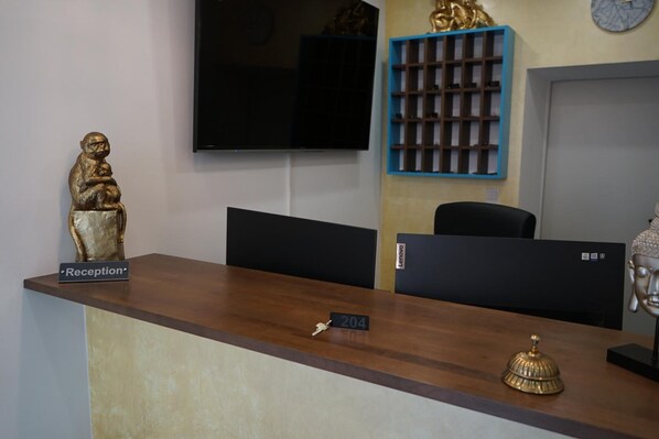 A reception desk with a 'Reception' sign, a statue, a Lenovo computer, and a clock on the wall. - Royal AM HBF (Nuremberg)