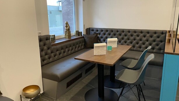 Un espace repas moderne comprenant une table en bois, deux chaises, un banc et une statue décorative.