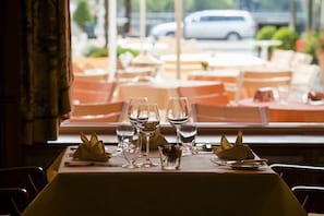 A table set for dining with wine glasses and a small bowl of fruit, overlooking a street with parked cars. - Insel-hotel Heilbronn (Heilbronn)