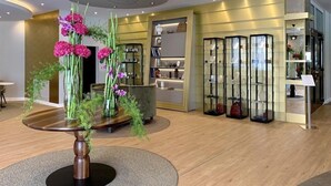 A modern interior with a central round table, glass display cabinets, and a ceiling light fixture. - Ringhotel Ostseehotel Ahlbeck (Heringsdorf)