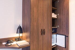 Une armoire en bois avec un miroir, un bureau avec une lampe et un réfrigérateur.