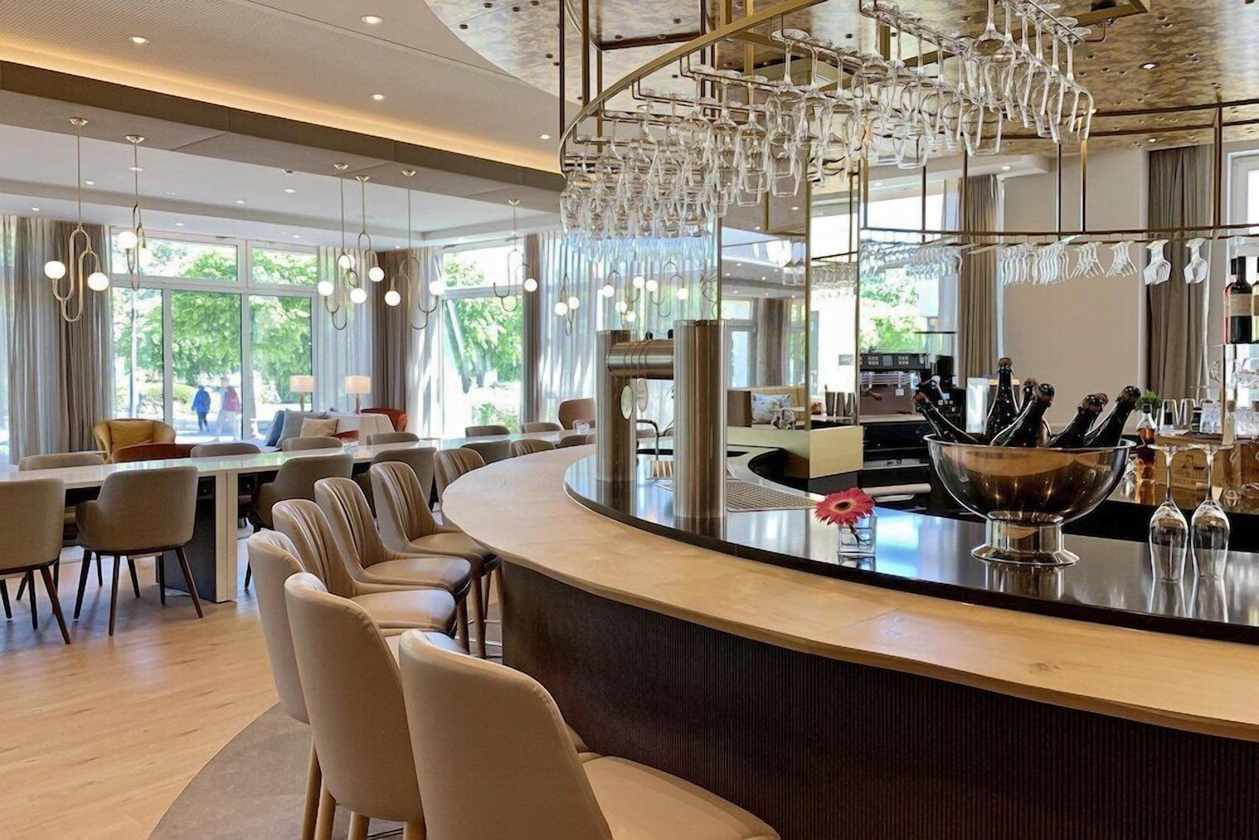 Eine moderne Bar mit gebogener Theke, Sitzgelegenheiten und einem außergewöhnlichen Kronleuchter.