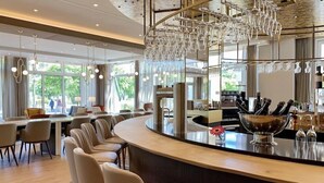 A modern bar area with a curved counter, seating, and a unique chandelier. - Ringhotel Ostseehotel Ahlbeck (Heringsdorf)