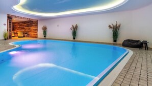 An indoor swimming pool with a curved ceiling, potted plants, and a seating area. - Ringhotel Ostseehotel Ahlbeck (Heringsdorf)