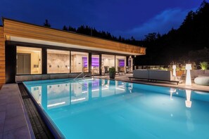 A modern building with a swimming pool, large windows, and outdoor seating. - Romantik Hotel Sackmann (Baiersbronn)