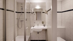 A modern bathroom with a glass-enclosed shower, a sink with a mirror above it, and a towel rack. - Hotel Newton Heilbronn (Heilbronn)