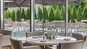An outdoor dining area with round tables, chairs, and umbrellas. - Hotel Newton Heilbronn (Heilbronn)