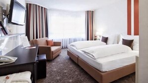 Une chambre d’hôtel avec un lit, un bureau, une chaise et un téléviseur.