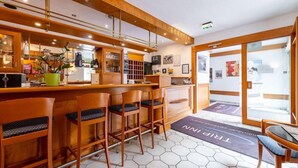 A hotel reception area with a wooden reception desk, bar seating, and a view through a glass door to the outside. - Hamm (Koblenz)