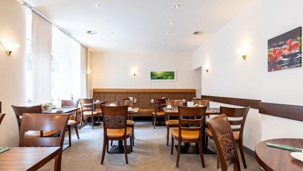 A restaurant with booths and tables, wooden chairs, and wall-mounted lights. - Hamm (Koblenz)