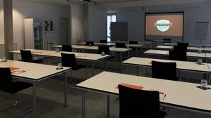 A conference room with tables, chairs, a projector screen, and a whiteboard.