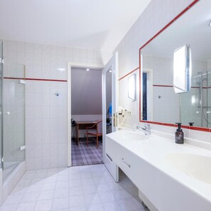 Une salle de bain moderne avec un grand miroir, deux lavabos et un espace douche.