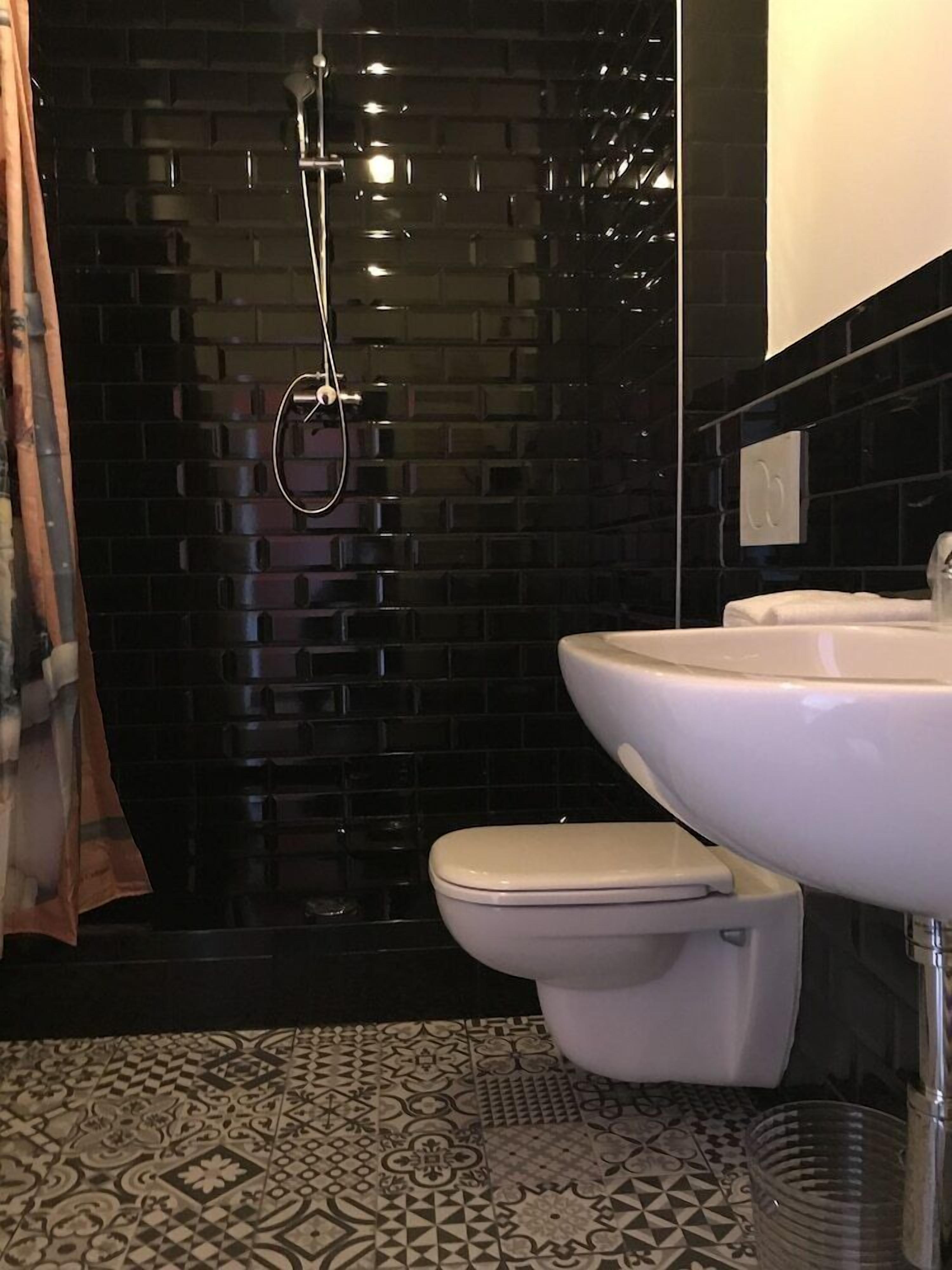 A bathroom with a black tiled wall, a white toilet, and a sink.