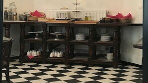 Una cocina con piso a cuadros blanco y negro, un cuadro en la pared y un candelabro.