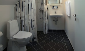 A bathroom with a toilet, shower, sink, and a towel hanging on the wall. - Aalbaek Badehotel, Sure Hotel Collection by Best Western (Aalbaek)