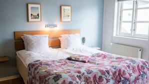 A bedroom with a wooden headboard, two white pillows, a floral bedspread, and two framed pictures on the wall. - Aalbaek Badehotel, Sure Hotel Collection by Best Western (Aalbaek)