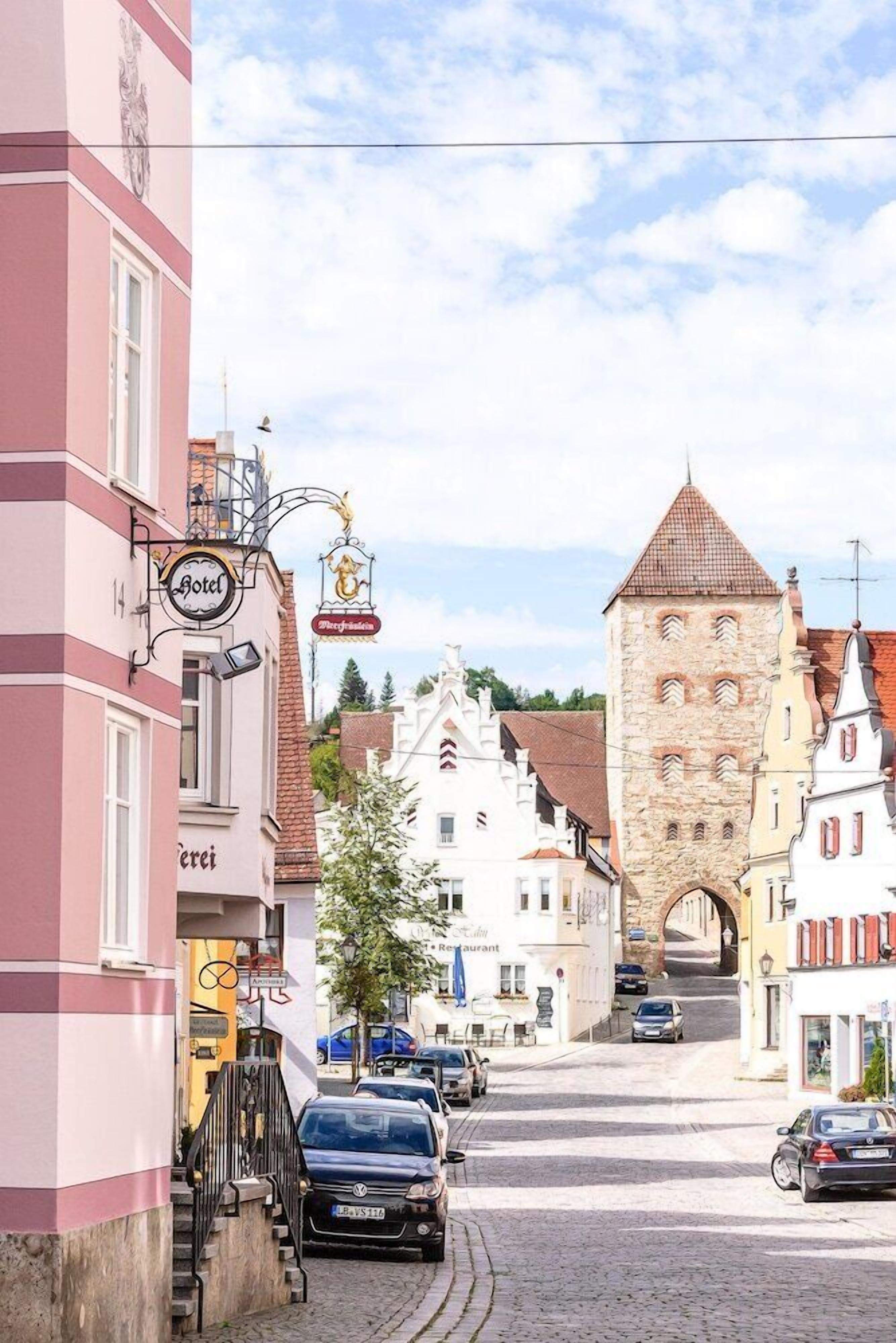 Une vue de rue avec une enseigne d’hôtel, une tour et des bâtiments à l’architecture traditionnelle.