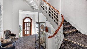 A grand staircase with a white balustrade and a chandelier, leading to a second floor. - Hotel Phnix Brnderslev (Bronderslev)