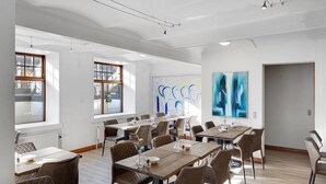 A modern dining area with multiple tables and chairs, large windows, and abstract art on the walls. - Hotel Phnix Brnderslev (Bronderslev)