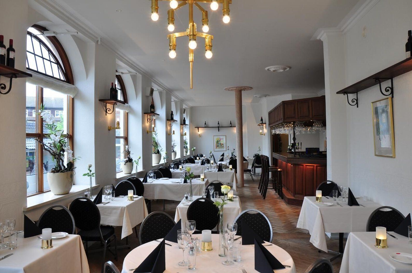 En restaurantindretning med flere borde, stole og en bar.