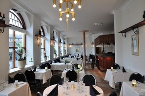 Un interior de restaurante con varias mesas, sillas y una zona de bar.