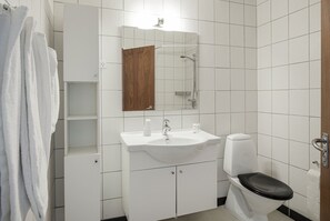 Un baño con lavamanos, espejo y retrete blancos.