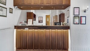 A reception area with a wooden counter, framed certificates on the wall, and a white textured wall. - Hotel Phnix Brnderslev (Bronderslev)