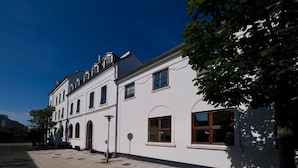 A white building with multiple windows and a tiled courtyard. - Hotel Phnix Brnderslev (Bronderslev)