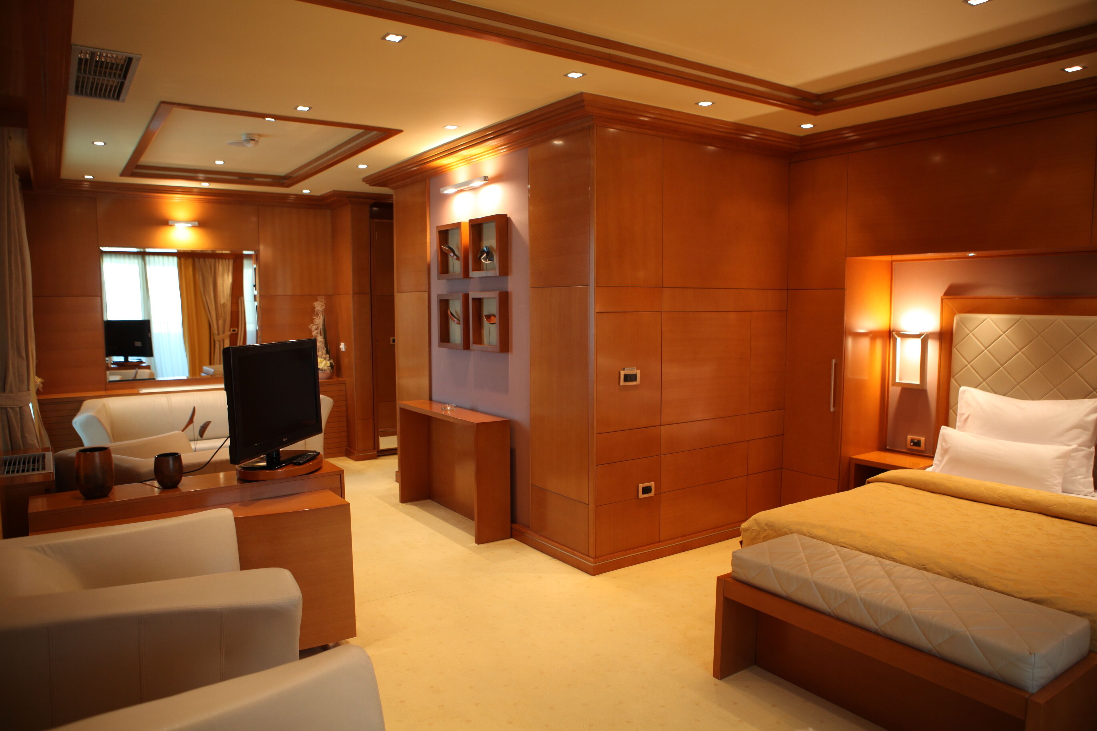 A hotel room with a bed, a TV, a desk, and a seating area.