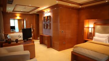 A hotel room with a bed, a TV, a desk, and a seating area.