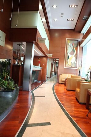 A modern lobby with a curved reception desk, seating area, and a large abstract painting. - Alexandar (Novi Sad)