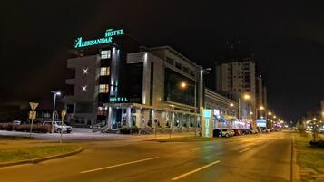 A modern hotel with a prominent sign, a well-lit entrance, and a parking lot.