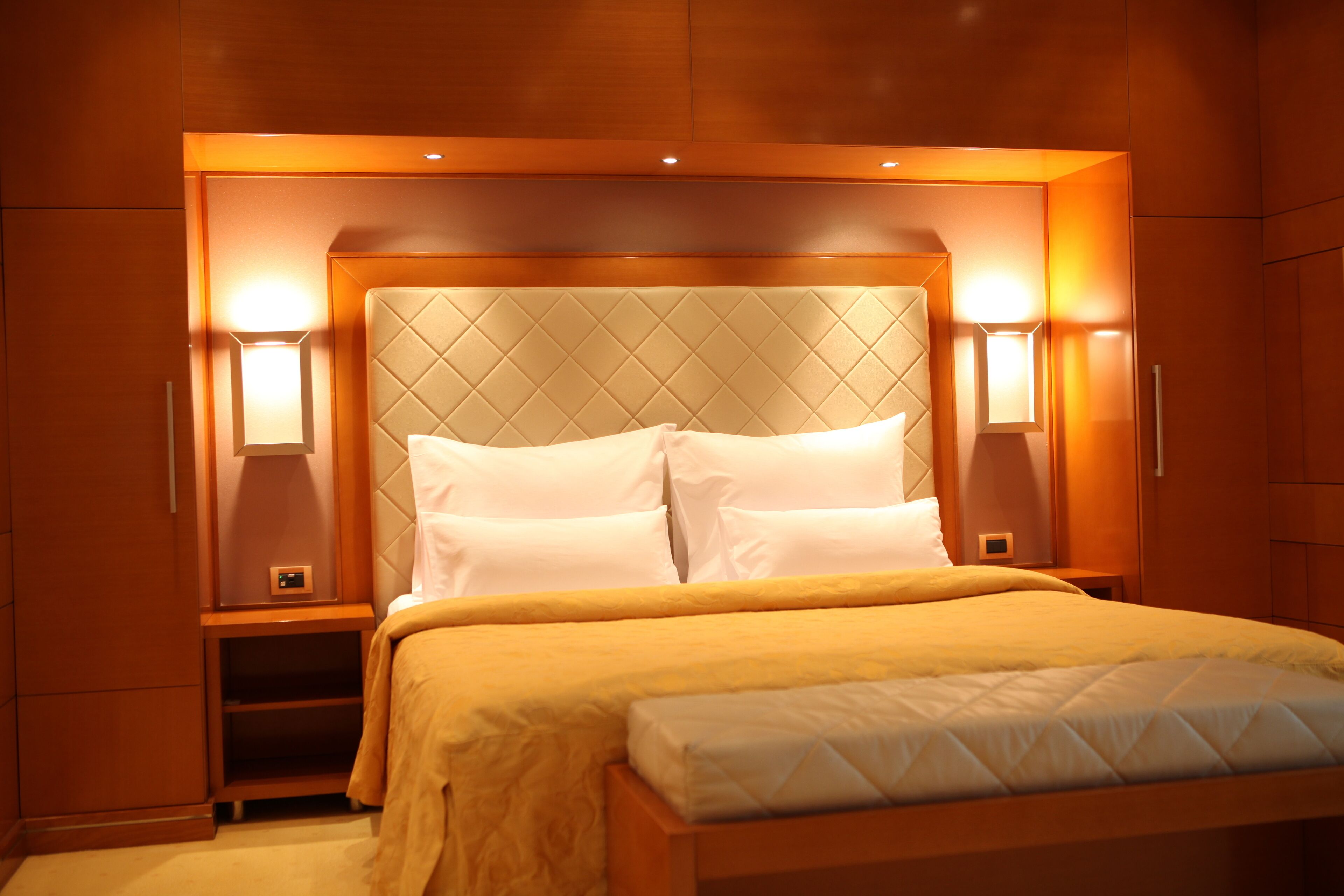 A hotel room with a large bed, two bedside tables, and wall-mounted lamps.