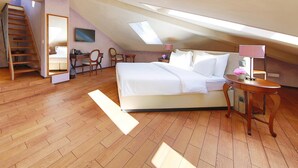 A bedroom with a sloped ceiling, a bed, a desk, two chairs, a small table, and a lamp. - Boutique Business Hotel La Tureta (Bellinzona)