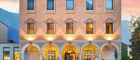A building with a central entrance, multiple windows, and outdoor seating with tables and chairs.