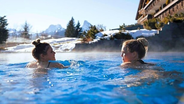 Two people in a hot tub with a mountainous backdrop. - Wellness Spa Hotel Ermitage (Saanen)