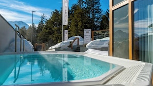 A swimming pool with a view of mountains, a sign for Hotel Sarain, and a wooden staircase leading to a covered area. - TOP Hotel Sarain Active Mountain Resort (Lantsch-Lenz)