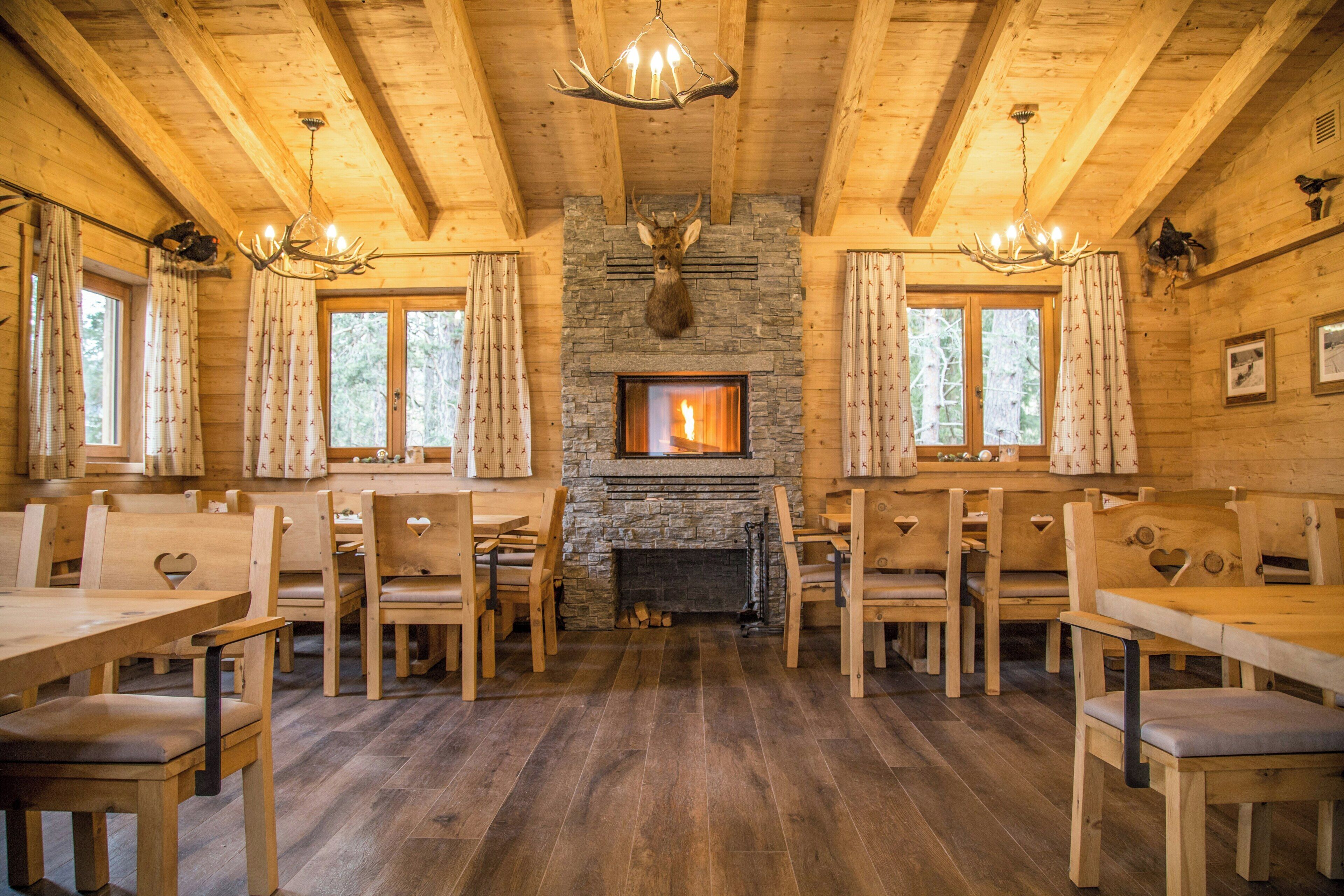A wooden interior with a stone fireplace, wooden furniture, and a chandelier.