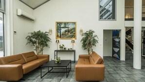 Un hall d’entrée spacieux, avec deux canapés en cuir, une table basse et deux plantes en pot.