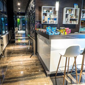 A modern hotel lobby with a marble floor, a reception desk, and a seating area with white chairs. - Arpesos (Kardzali)